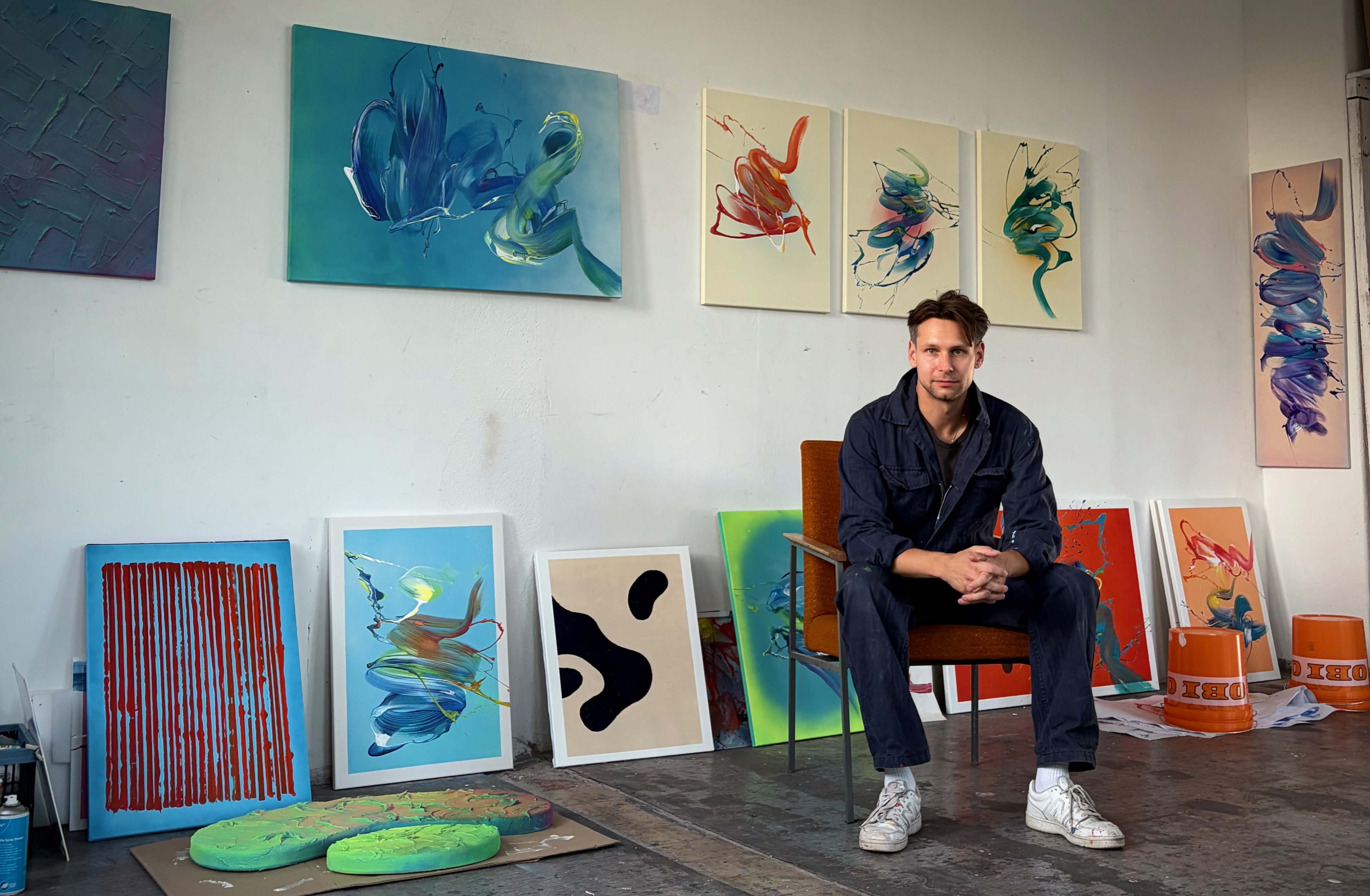 Maximilian Tischer seated in his Berlin studio among finished and in-progress abstract paintings